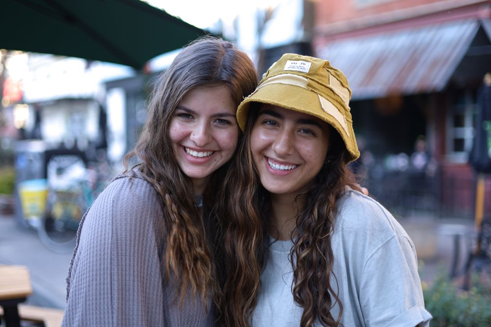 Two friends smiling together under a cafe umbrella