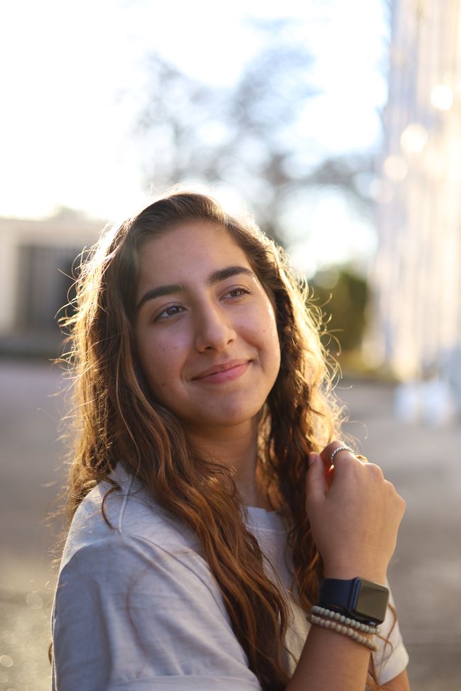 Woman in a white tee smiling in low golden light