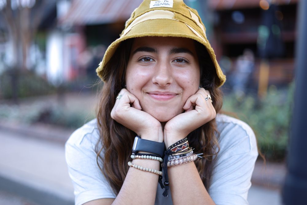 Woman in a yellow bucket hat resting her chin on her hands