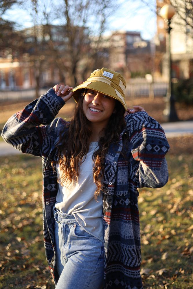 Woman in a plaid shacket and bucket hat among fallen leaves