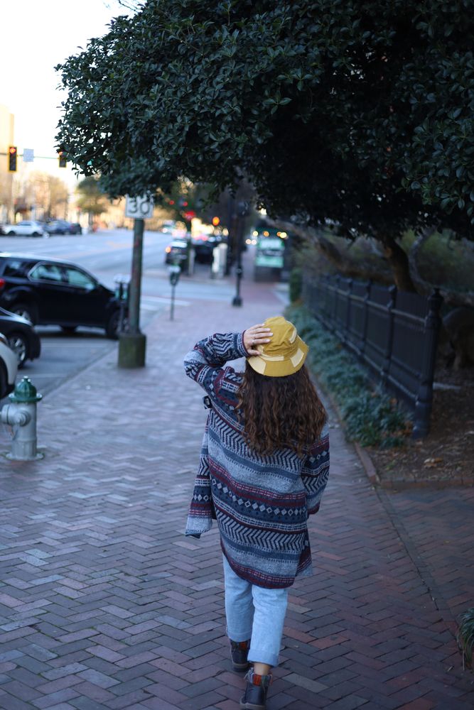 Woman walking away down a brick sidewalk