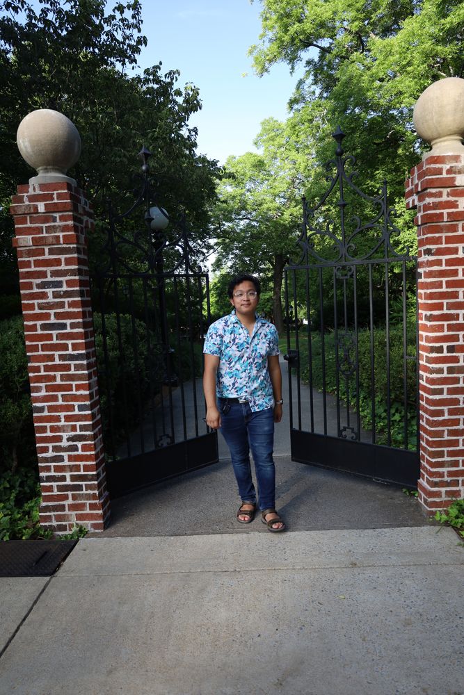 Man standing between brick gate pillars in evening light