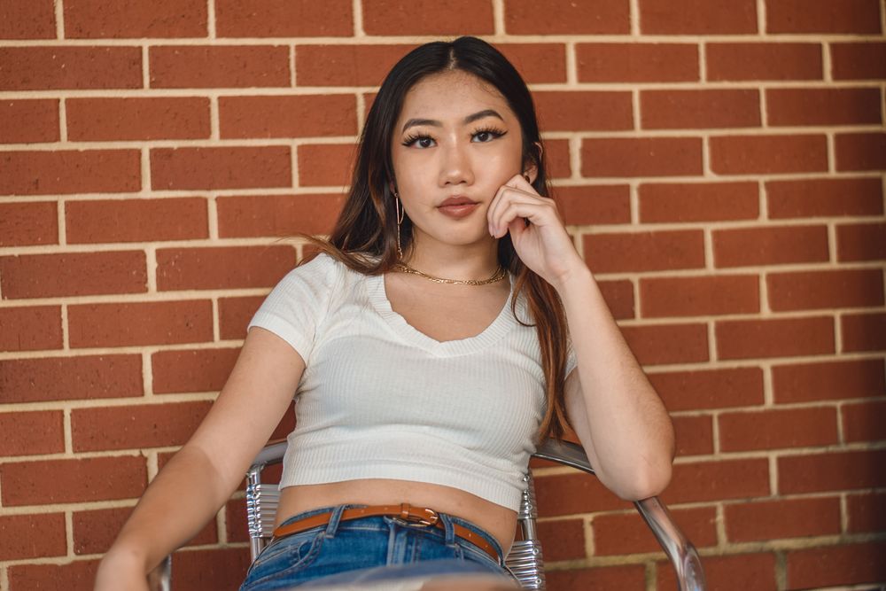 Woman seated against a red brick wall