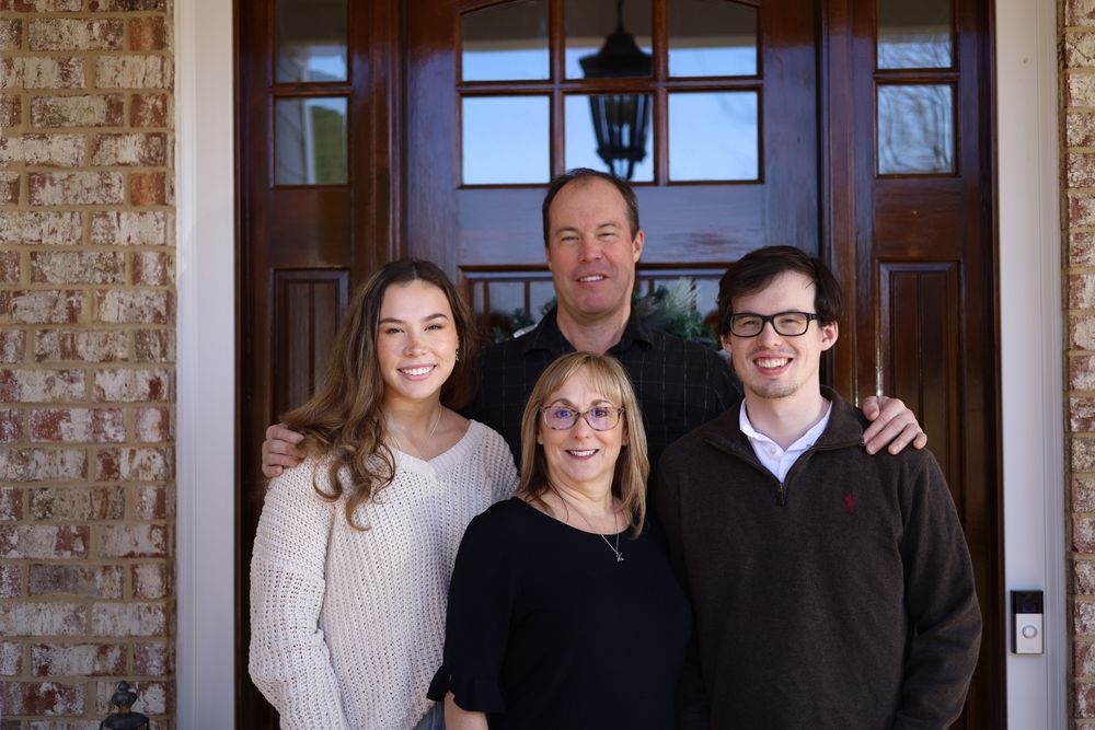 Family of four on their front porch at Christmas