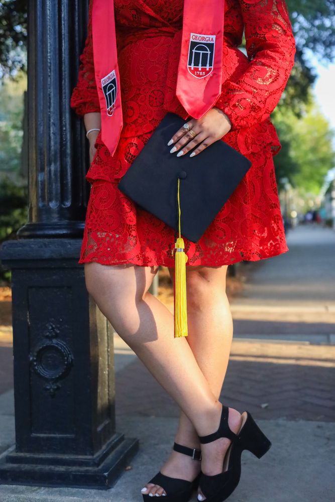 Close-up of a graduate holding her cap against a red lace dress