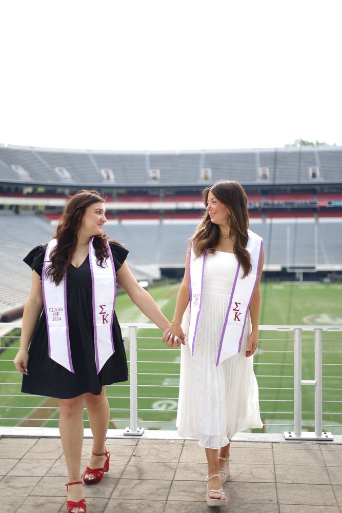 Two graduates in stoles walking through a stadium