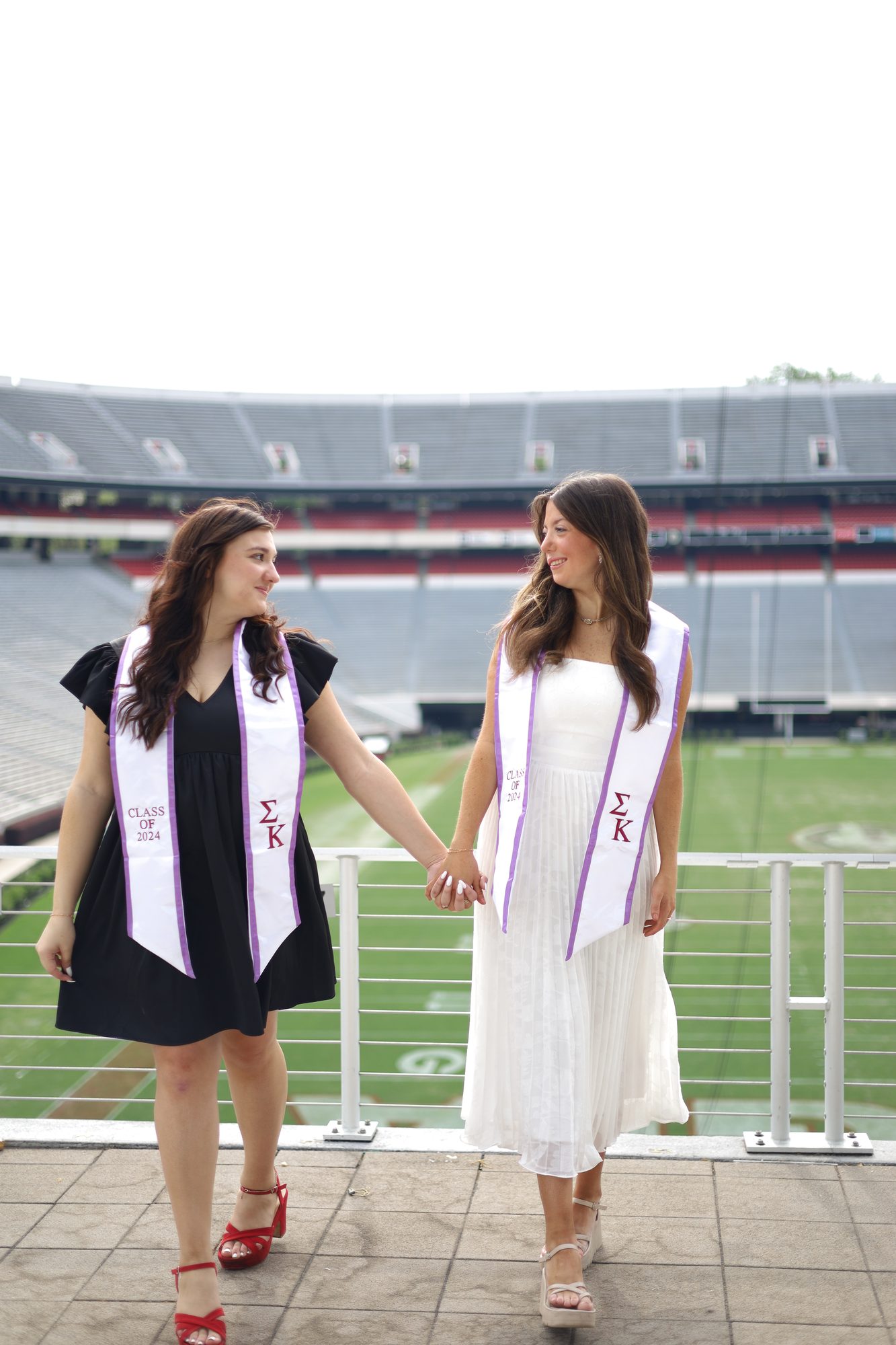 Two graduates in stoles walking through a stadium