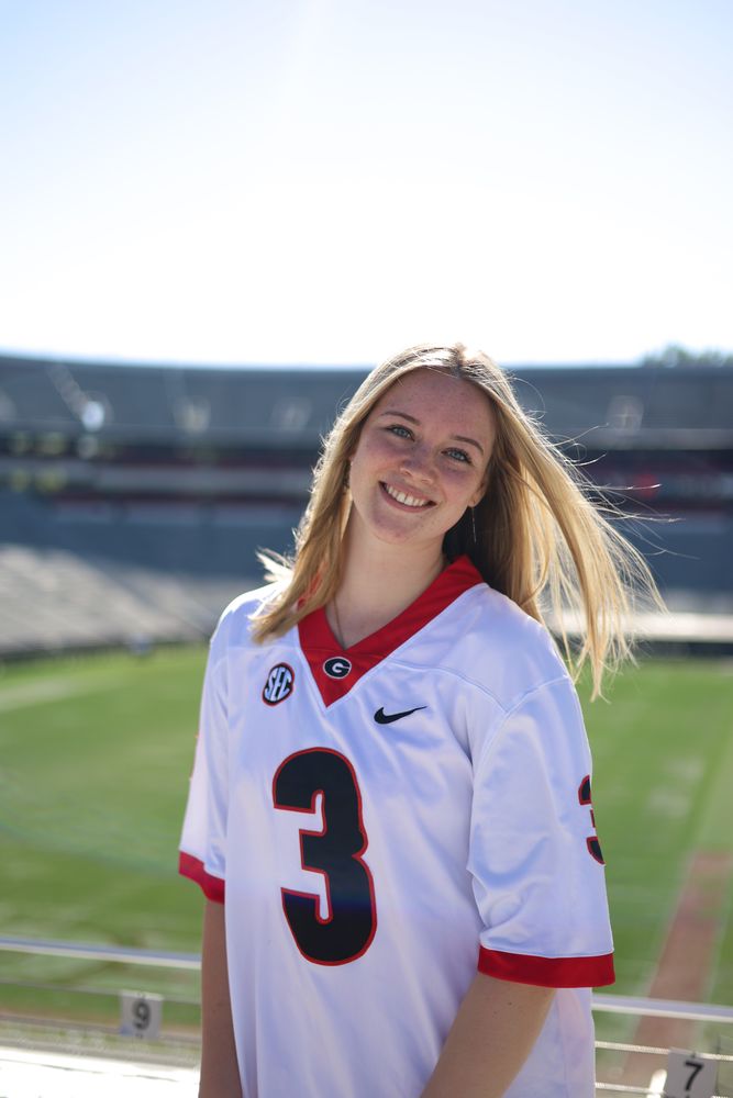 Smiling graduate in a number 3 jersey in a stadium