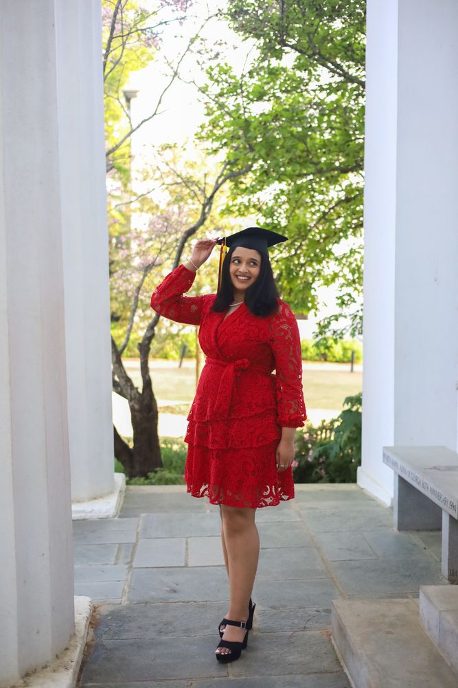 Graduate in a red dress and cap between columns