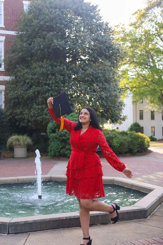 Graduate tossing her cap in front of a fountain