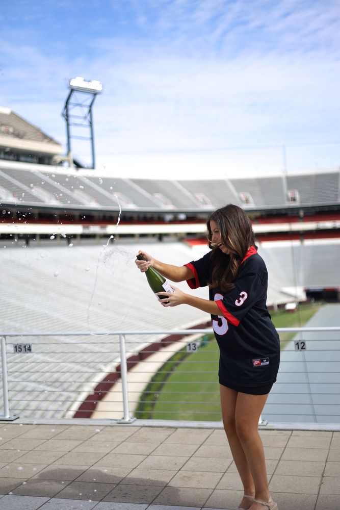 Graduate popping champagne in a stadium