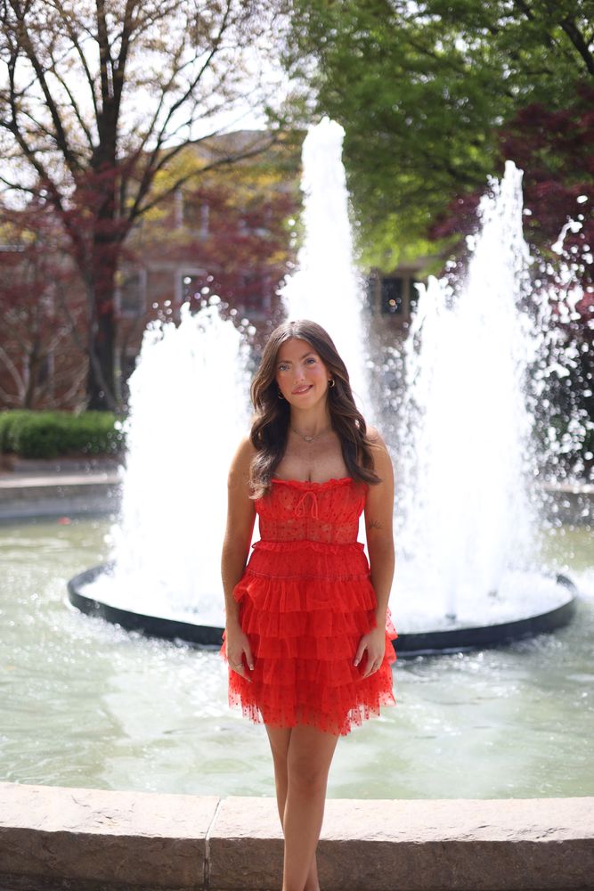 Graduate in a red dress in front of a fountain