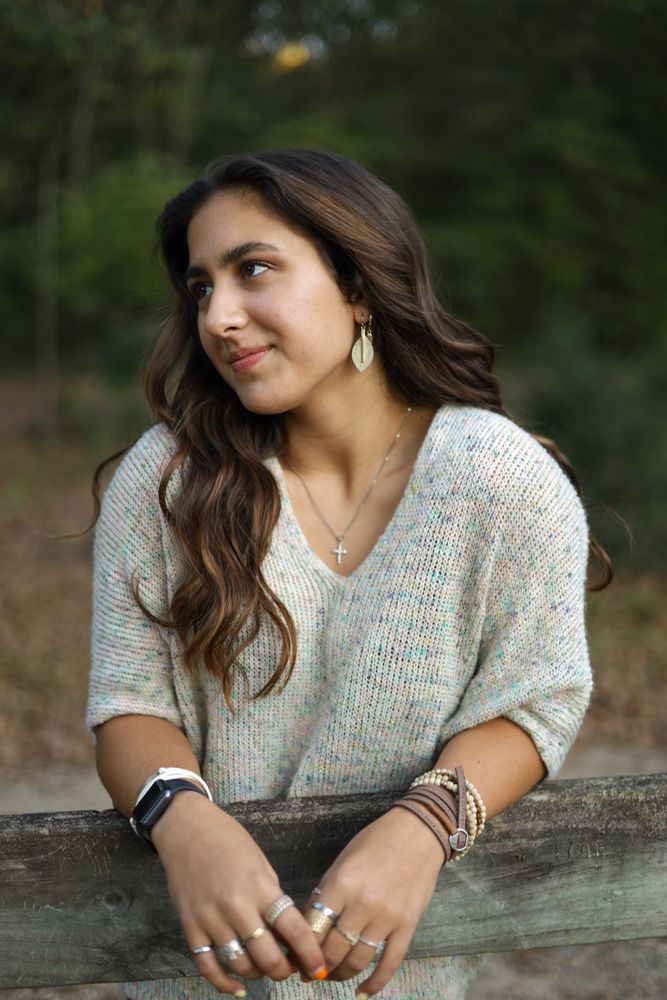 Woman leaning on a wooden fence looking off camera