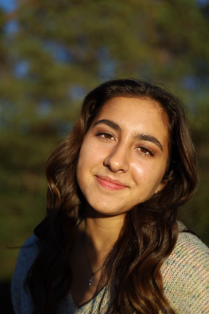 Close portrait of a woman in a knit sweater against dark foliage