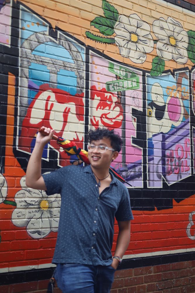 Man in a blue shirt in front of a postcard mural