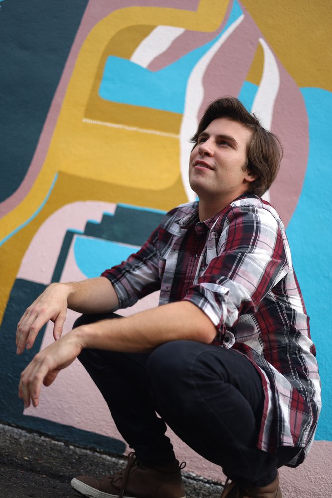 Man crouching in front of a geometric mural