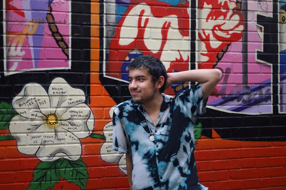 Man in a tie-dye shirt against a bright mural