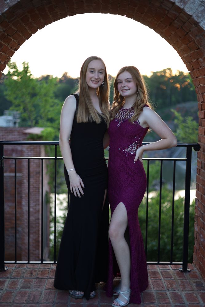 Two friends in gowns on a brick terrace at sunset