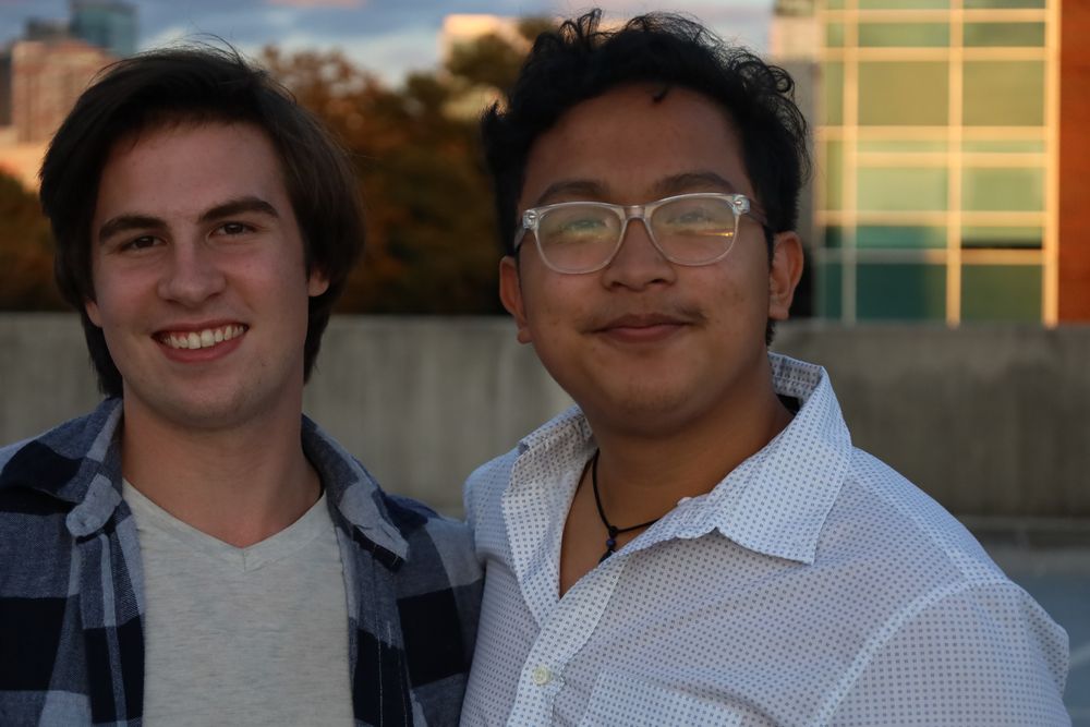 Two friends crouching on a parking deck at golden hour