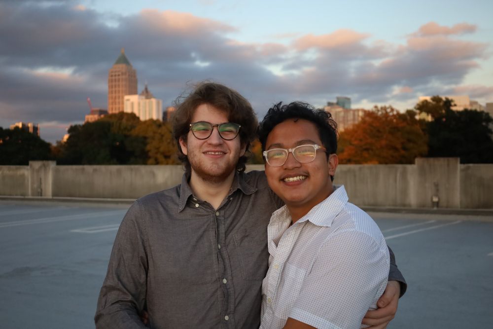 Two friends smiling with the Midtown skyline behind them