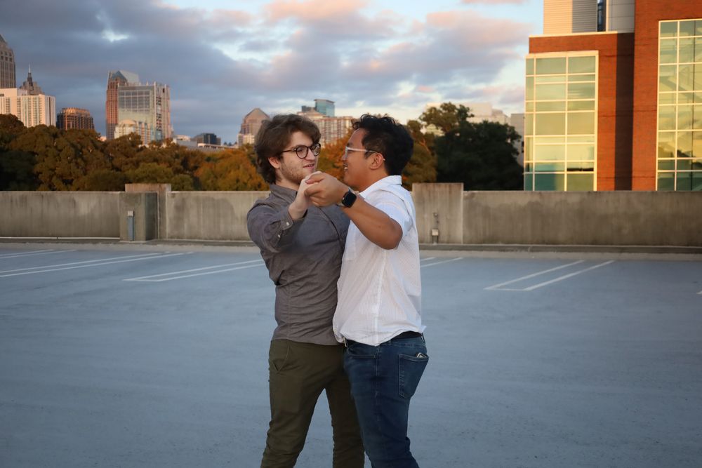 Two friends goofing around on a rooftop at sunset