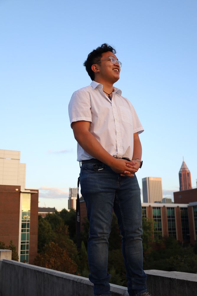 Man in a white shirt standing on a parking-deck ledge above the Atlanta skyline