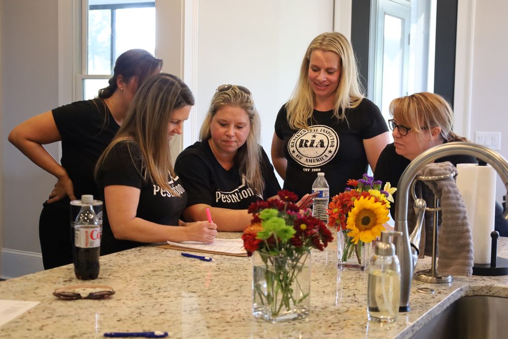 Four coworkers in matching shirts signing papers at a kitchen island