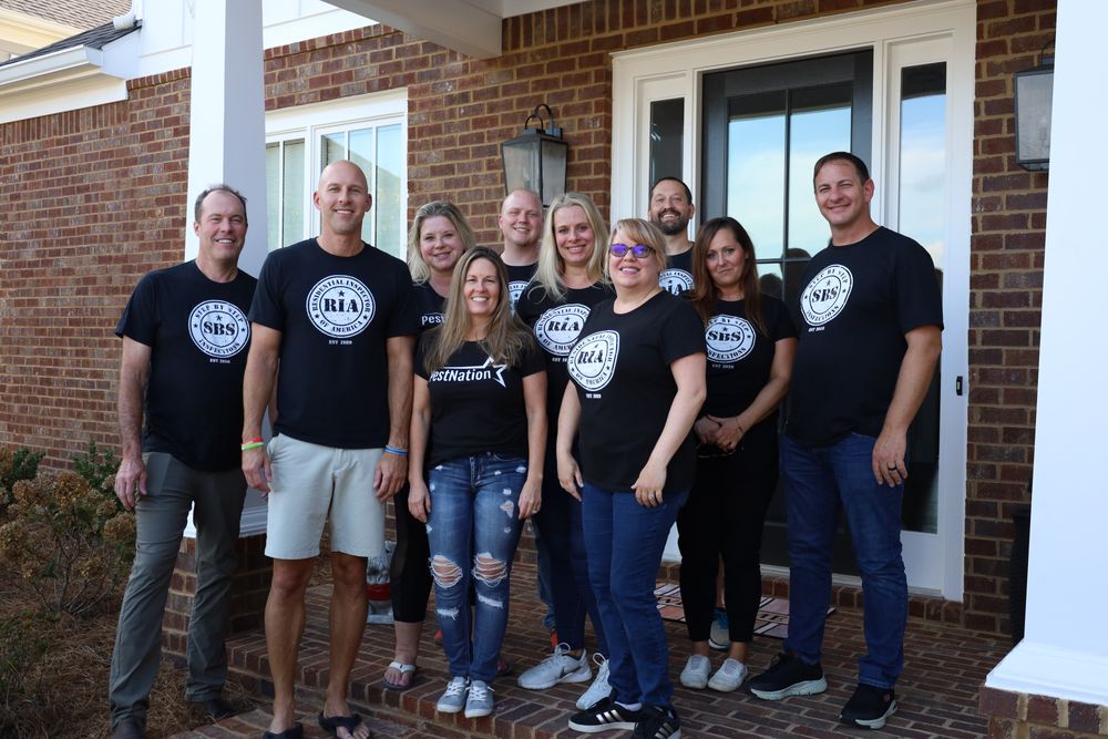 A team of eight in matching black shirts on a brick porch