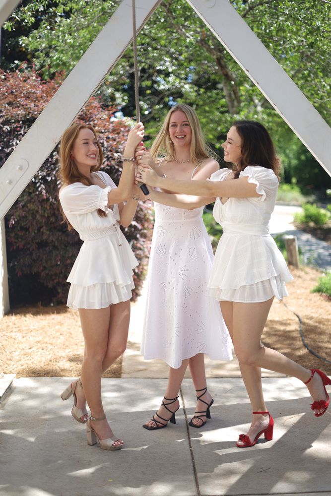 Three friends posing under the trellis arches