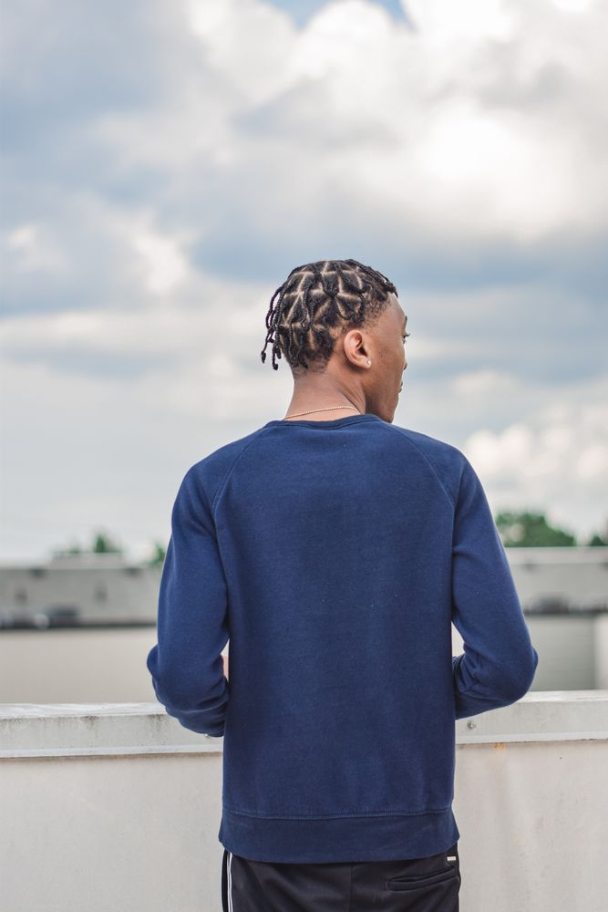Man looking out over a rooftop under a cloudy sky