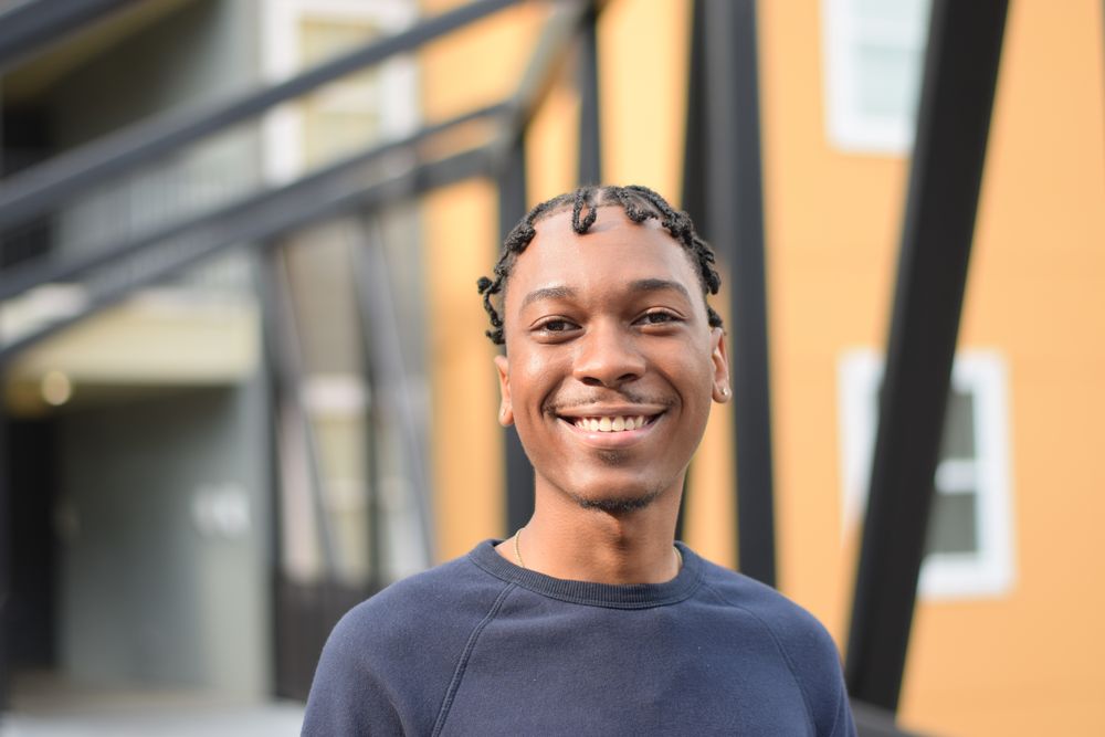 Smiling man in front of an orange building