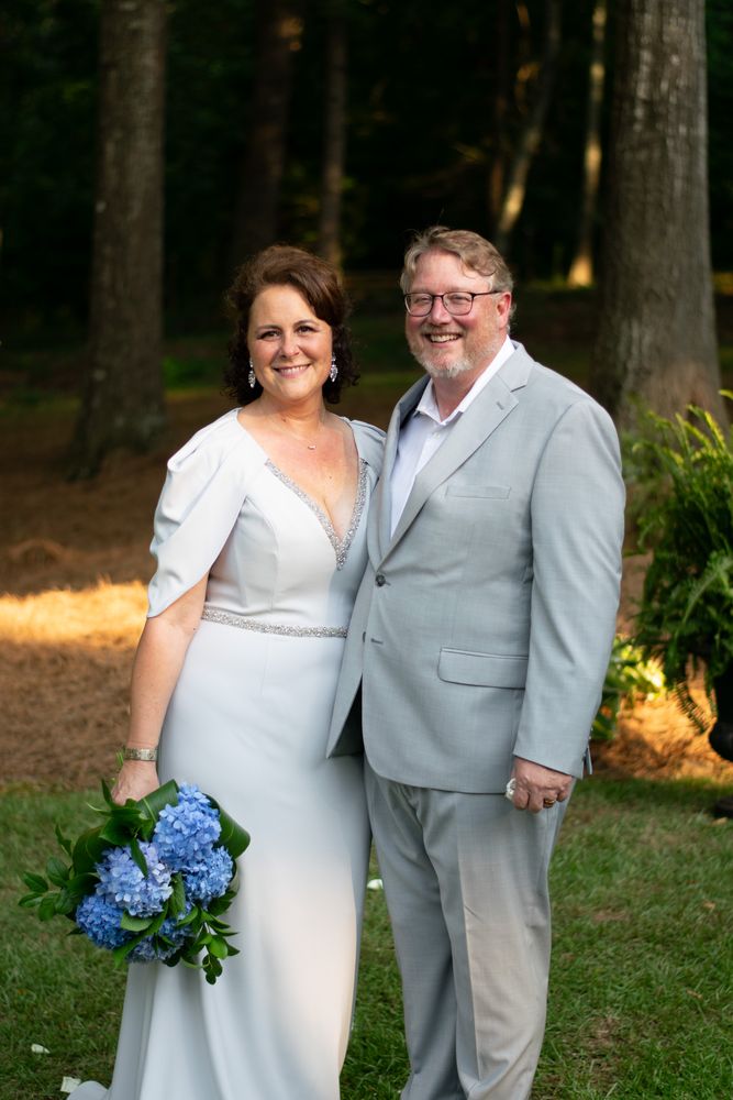 Newlyweds standing together among tall pine trees