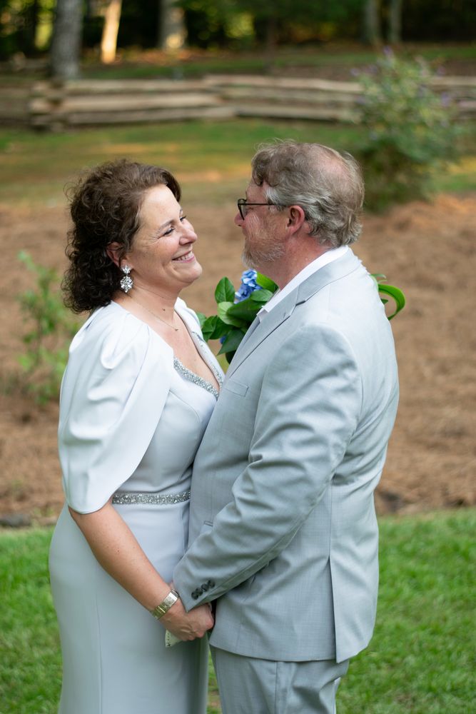Bride and groom embracing and smiling in a backyard