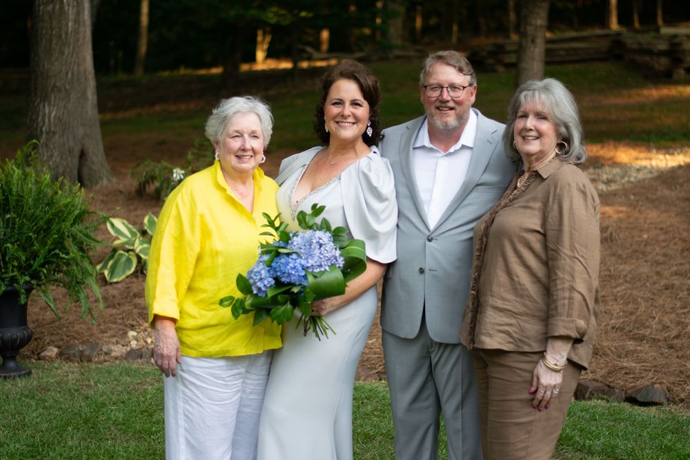 Wedding couple with their mothers on the lawn at sunset