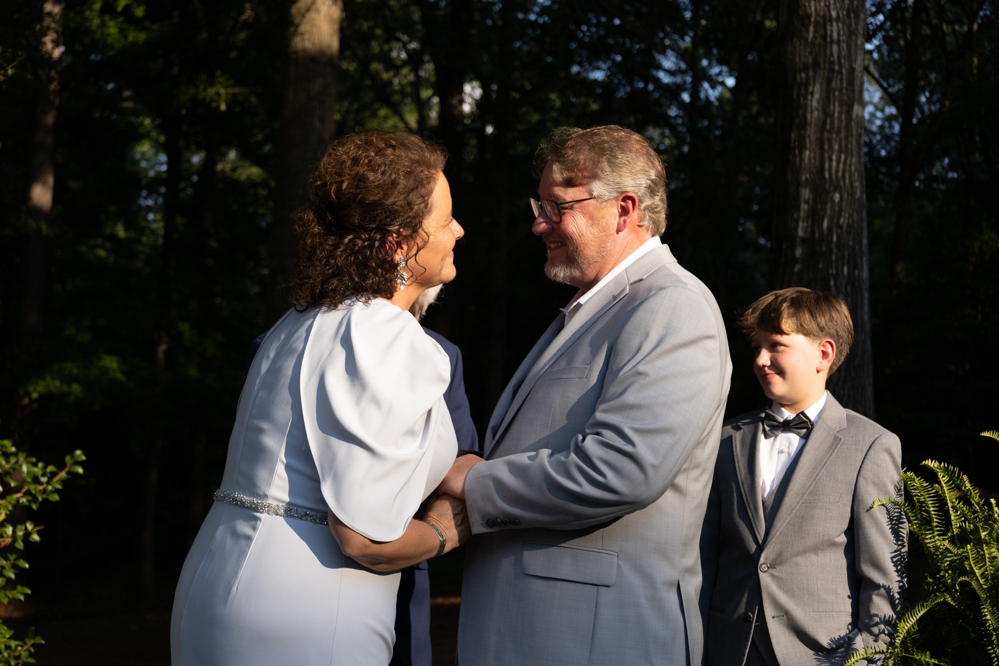 Couple exchanging vows at an outdoor wedding as their son looks on